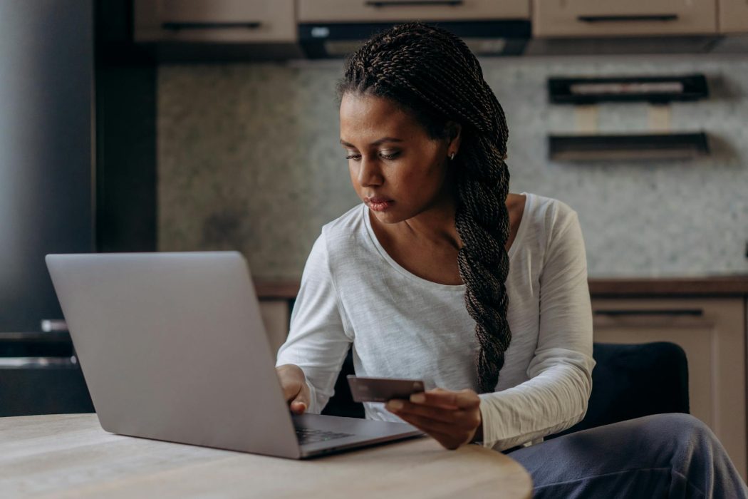 woman using her laptop while holding her credit card
