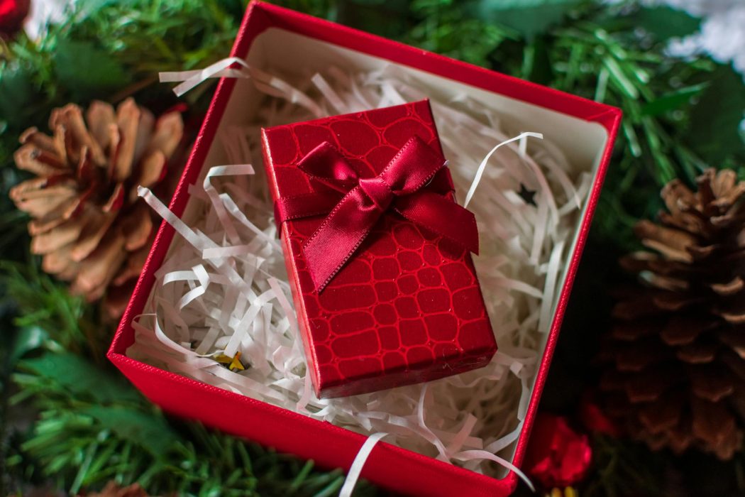 festive red gift box with pine cones and greenery